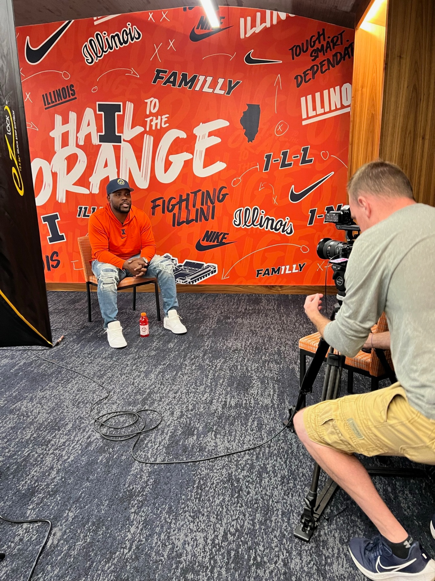 Isiah Williams seated for a filmed interview in front of a Fighting Illini backdrop