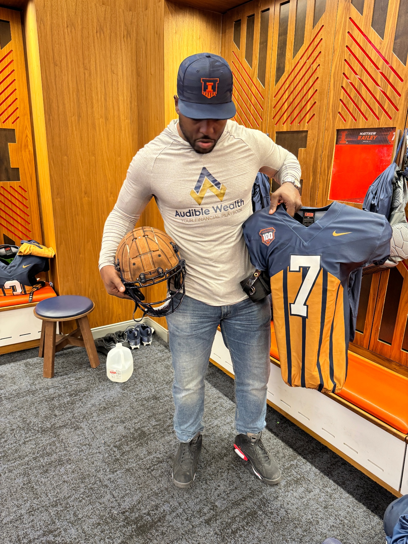 Isiah Williams holding his number 7 Illinois jersey in the team locker room