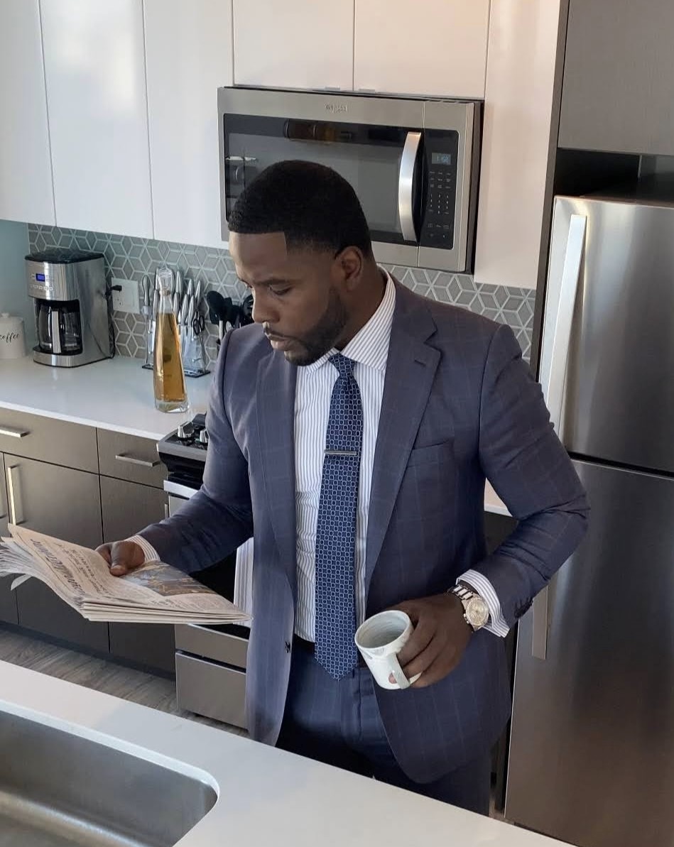 Isiah Williams reading the morning paper in a suit before the workday