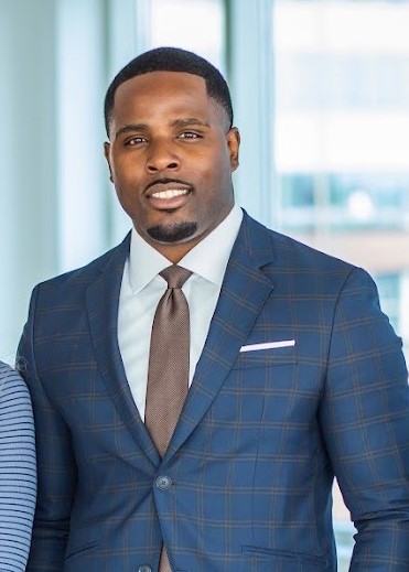 Isiah Williams in a navy plaid suit in a glass-walled office lobby