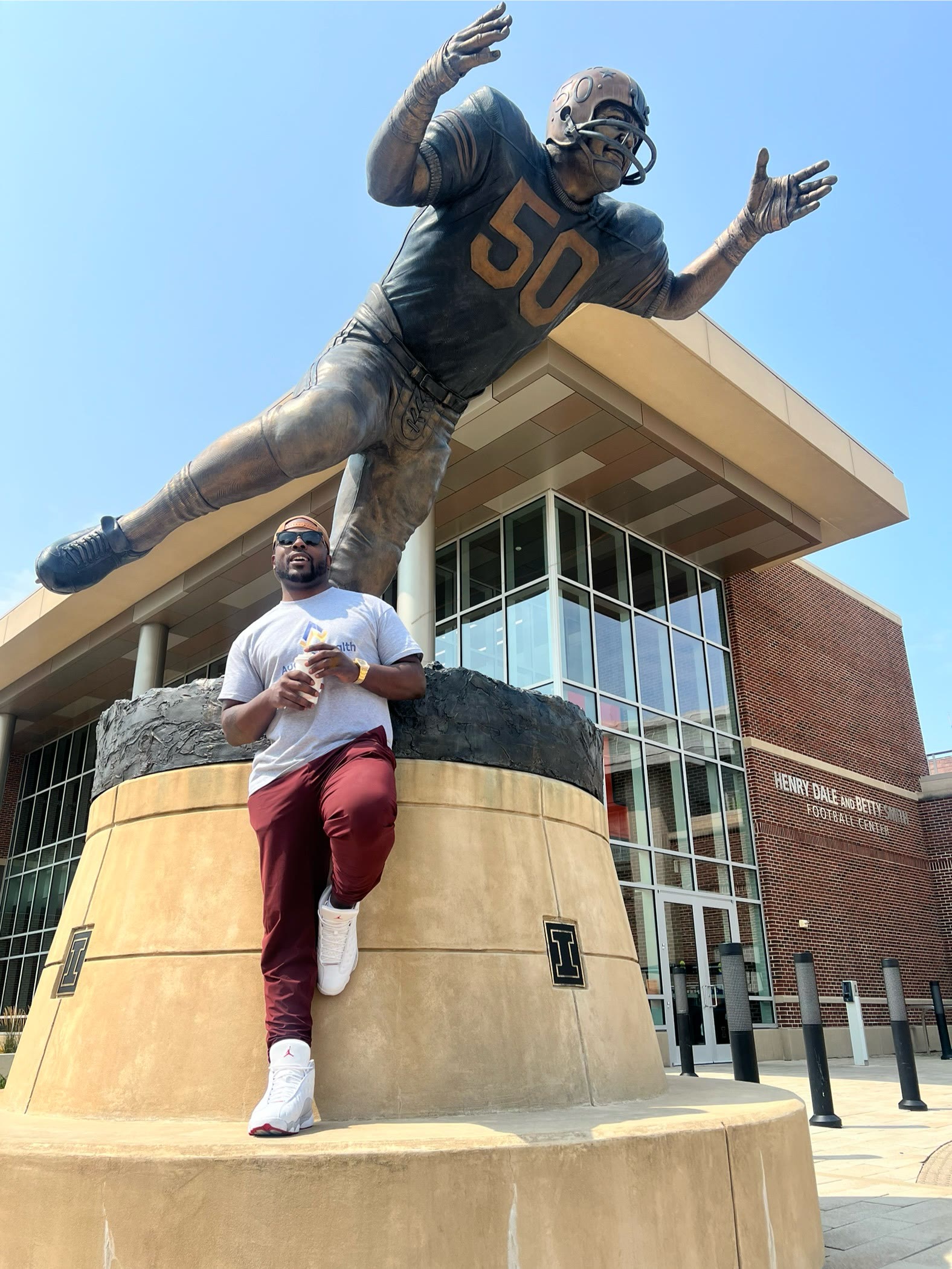 Isiah Williams seated at the Dick Butkus statue outside the Illinois football center